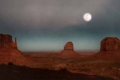 A full moon rises over Monument Valley.