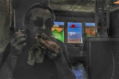 A man eating a fast food burger in the Mojave desert with windmills.